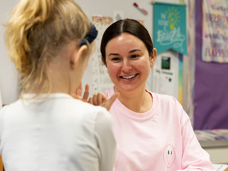 A teacher smiles as she works one-on-one with a student