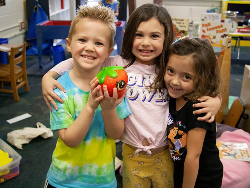 Three Early Childhood students gather together in their classroom