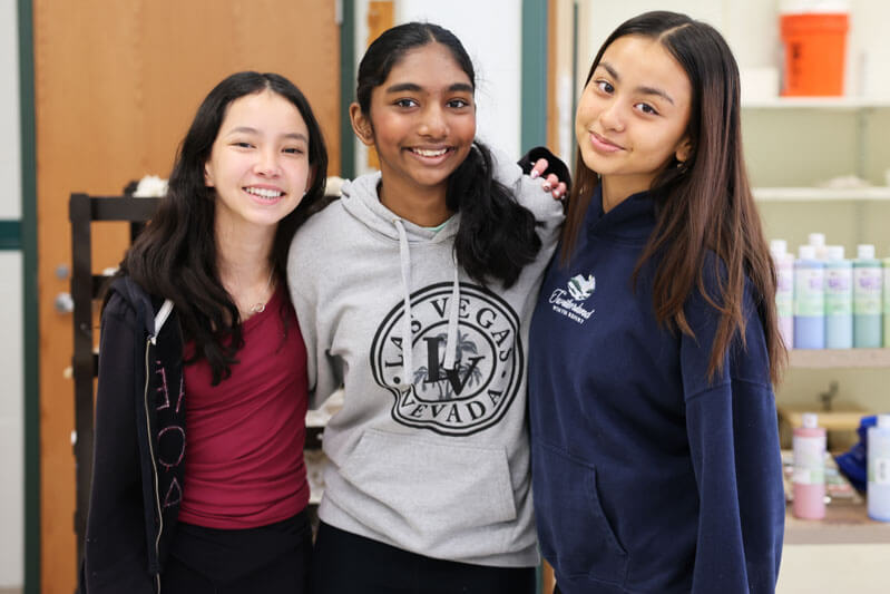 Three Wildwood students smile together in class